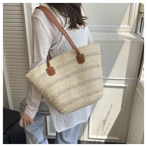Detailed shot of beige woven tote bag with premium brown leather straps and fine stitching