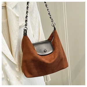 Detail of caramel suede tote bag with black leather flap and silver woven chain strap