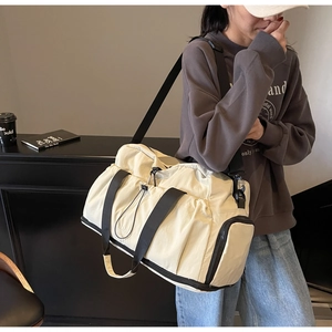 Off-white large travel bag with black straps worn by model for short trips or fitness