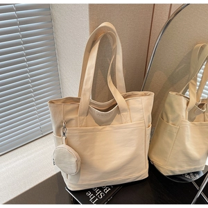 Detail view of cream canvas tote bag with multi-pockets and a small round coin purse