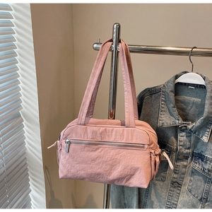 Pink nylon tote bag detail with horizontal zipper pocket and drawstring side pouch