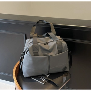 Detail of gray waterproof nylon travel bag featuring spacious pockets and round logo