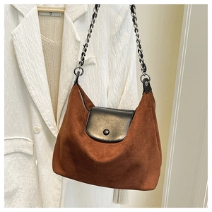 Detail of suede tote with black leather flap and silver interwoven chain strap
