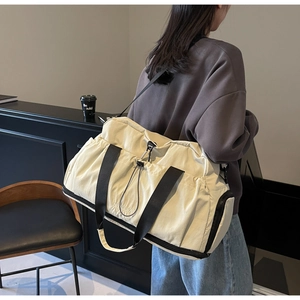 Detail of a large off-white canvas travel bag with durable black straps and logo