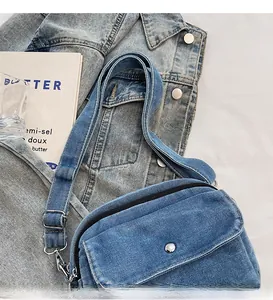 Detail of blue denim crossbody bag with silver buckle on a matching denim jacket