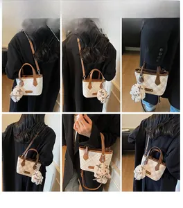 Detail view of mini checkerboard tote bag with brown leather trim and bear pendant