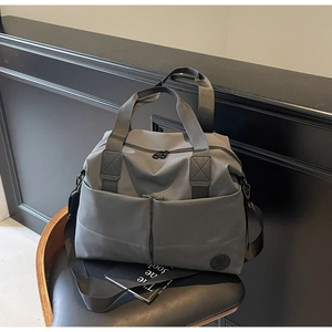 Close-up of a dark grey travel bag featuring reinforced handles and dual front pockets