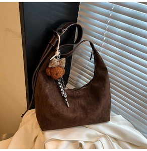 Detail of dark brown suede hobo bag featuring fine stitching and cute bear charm