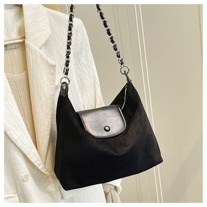 Detail of black suede hobo bag featuring chain strap on white blazer hanger