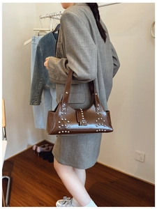 Detail view of brown biker shoulder bag with silver rivet studs and glossy finish