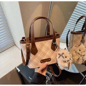 Detail of checkered tote bag with pink faux leather trim and plush rabbit keychain