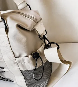 Detail of durable D-ring hook, nylon strap and mesh side pocket on beige travel bag
