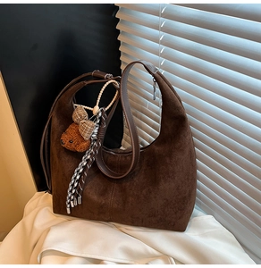 Detail view of dark brown suede hobo bag texture with a cute plush bear charm on white silk