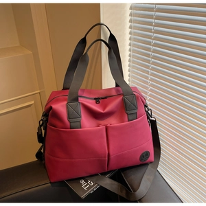 Detail of a magenta travel bag showing waterproof fabric texture and adjustable shoulder strap