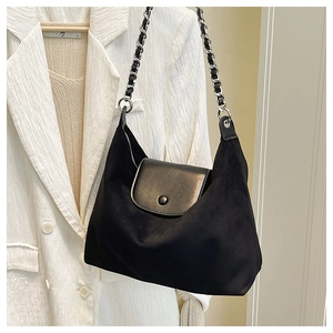 Detail of black trapezoidal tote bag showing matte texture and silver chain strap