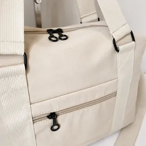 Detail of light beige travel bag with high-quality nylon texture and metal hardware