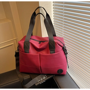 Close-up of waterproof magenta travel bag with reinforced handles and brand logo