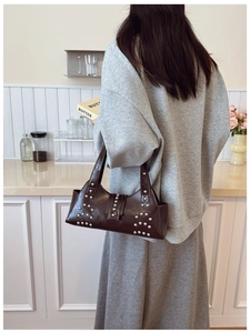 Detail shot of a vintage brown leather bag with silver rivets in a lifestyle scene
