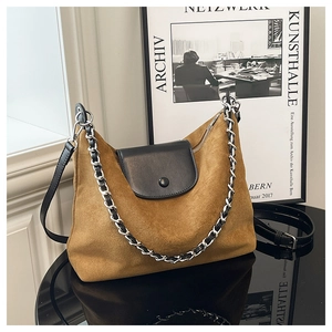 Detail view of brown suede tote bag with black leather flap and silver chain accent