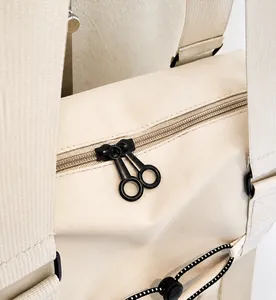 Detail of smooth black circular zipper on cream textured nylon bag with a macro view