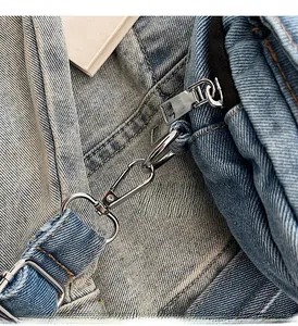 Macro detail of high-quality polished silver metal hardware on a denim crossbody bag