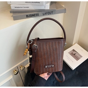 Detail of dark brown woven bucket bag with elegant wooden beads and round leather handle