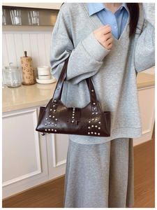 Close-up of dark brown leather handbag featuring silver studs and retro buckle details