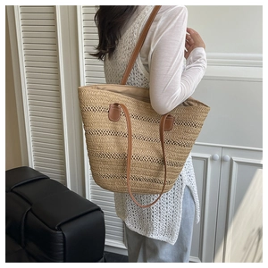 Detail of the woven straw texture and premium brown leather straps on a large tote bag