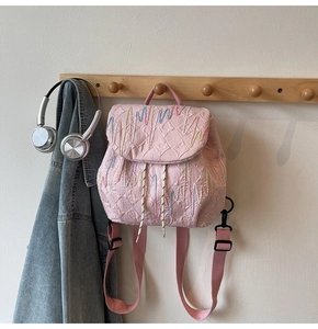 Detailed view of pink pleated mini backpack with letter embossing and multi-color embroidery