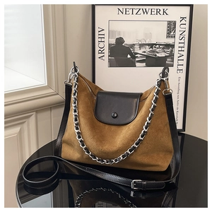 Detailed macro view of the brown suede surface and black leather flap with silver chain