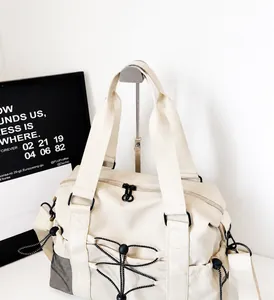Detail of cream nylon travel bag featuring adjustable front bungee cords and mesh pockets