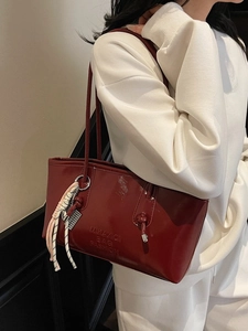 Deep red patent leather tote bag with glossy finish and stylish braided rope charm