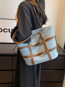 Retro denim tote bag with brown leather lattice and gold studs shown on a model's shoulder