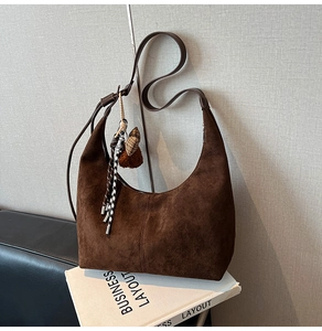 Detail view of large dark brown suede hobo bag with teddy bear and houndstooth charms
