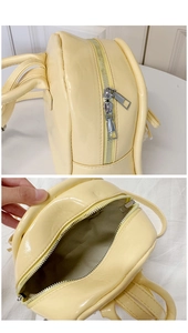 Détail du cuir verni jaune avec double fermeture éclair métallique sur le sac à dos