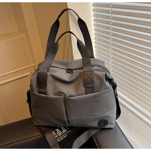 Close-up of a large grey nylon travel bag featuring dual handles and open front pockets