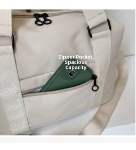 Detail of beige nylon travel bag showing functional front zipper pocket with a smartphone