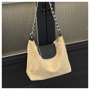 Detail of beige suede hobo bag featuring black leather flap and silver chain strap