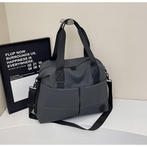 Detail of waterproof nylon travel bag featuring dual front pockets and detachable strap