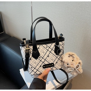Detail of checkerboard tote bag with polka dots, metal logo, and plush rabbit charm