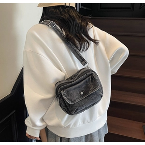 Detailed view of dark grey washed denim crossbody bag with double zippers and flap pocket