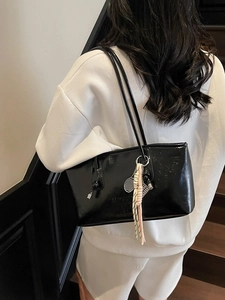 High-gloss black leather tote bag with logo embossing and decorative tennis racket charm