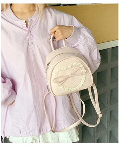 Détail d'un mini sac à dos rose avec dentelle en cœur et nœud porté par un mannequin