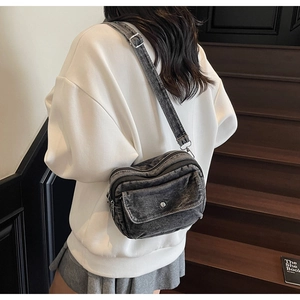 Washed denim crossbody bag in black-grey finish shown from behind on a model