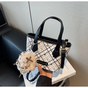 Close-up of checkerboard tote bag featuring metallic logo and plush pearl charm