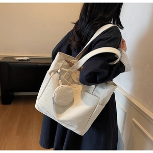 Detail of beige canvas tote bag with side pocket and matching small round pendant purse