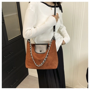 Brown suede tote bag with black flap and silver chain detail shown on a model