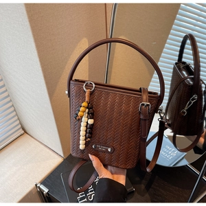 Detail of a brown woven bucket bag featuring round handles and colorful wooden beads
