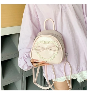Détail d'un mini sac à dos rose avec dentelle en cœur et nœud porté par un modèle