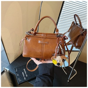 Detail van bruine vintage leren crossbodytas met hondenpenning en mode-embleem